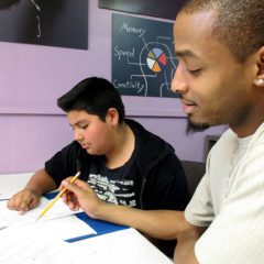 Young man helping high school boy with homework