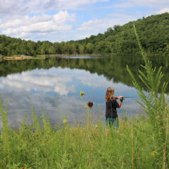 Child fishes in scenic lake