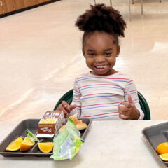 A young girl enjoys a healthy lunch.